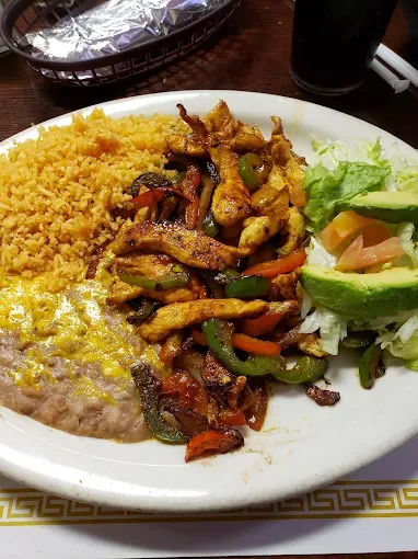 Chicken fajita plate with grilled peppers and onions, Mexican rice, refried beans and sliced avocado