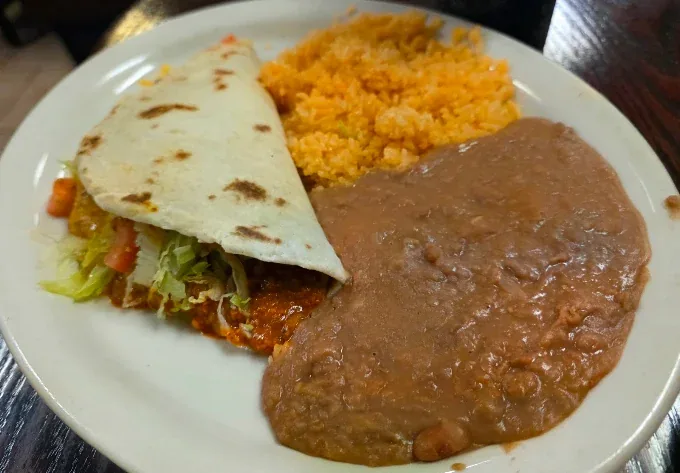 Soft chorizo taco with lettuce and tomato, served with Mexican rice and refried beans